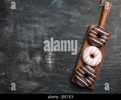 Donuts on cutting board over black background. Top view with copy space Stock Photo
