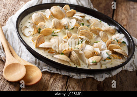 Delicious clams in a creamy sauce with parsley closeup on a plate on a table. horizontal Stock Photo