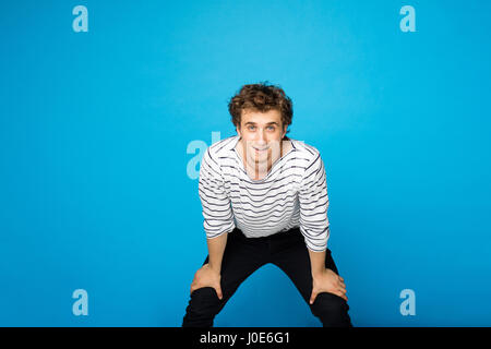 young curly lively guy with sailor shirt on blue background Stock Photo