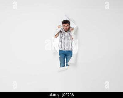 casual man in stripes and jeans breaking the paper wall Stock Photo