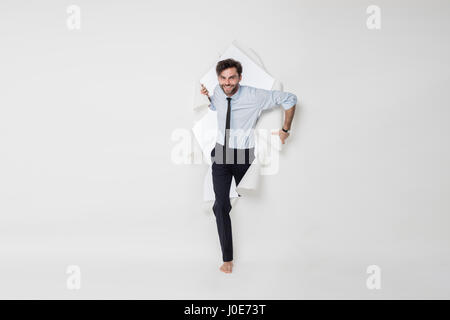 young office man with tie and barefoot breaking the paper background, passing from side to side Stock Photo