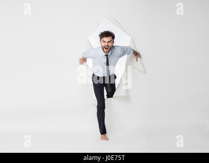 young office man with tie and barefoot breaking the paper background, passing from side to side Stock Photo