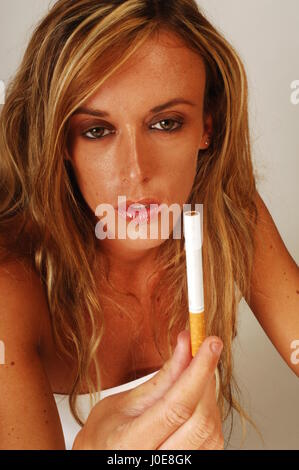 Young blonde woman smoking a cigarette, smiling Stock Photo - Alamy
