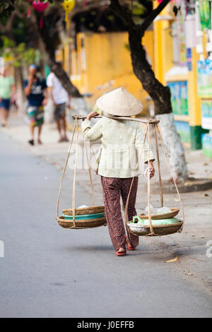 Hoi An, Vietnam - march 14 2017: vietnamese woman is carrying goods in traditional way. Stock Photo
