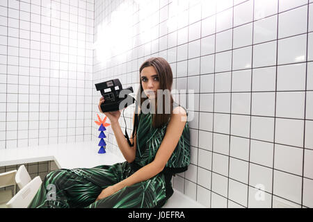 Beautiful young woman witn photo camera sitting on the table in cafe Stock Photo