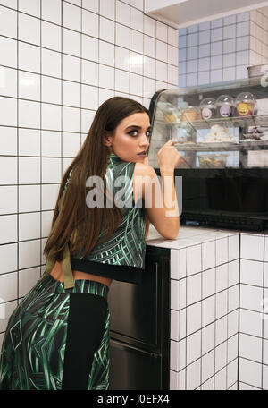 Attractive young woman standing and choosing dessert near the counter in cafe Stock Photo