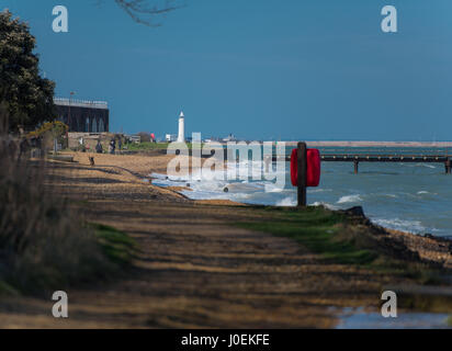 A Blustery day by the sea, people out for walks with their dogs, taking in the views of the lighthouse and beautiful scenery around them. Stock Photo