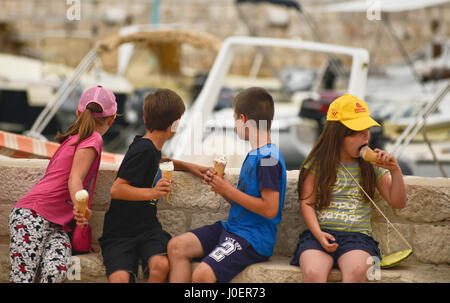 School kids eating ice cream during an excursion. Hvar Town, Croatia Stock Photo