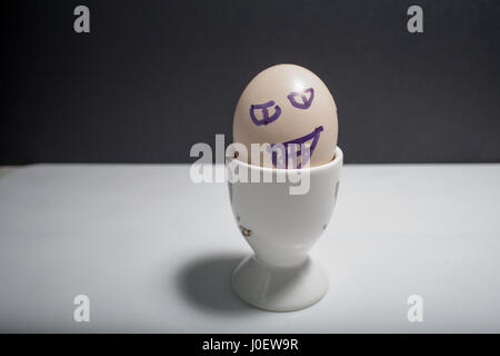 Egg standing on egg cup, isolated on white background Stock Photo