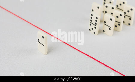 Expelled from the group, unable to cross the red line that separates them. Scene with group of domino. Concept of accusation guilty person, bulling or Stock Photo