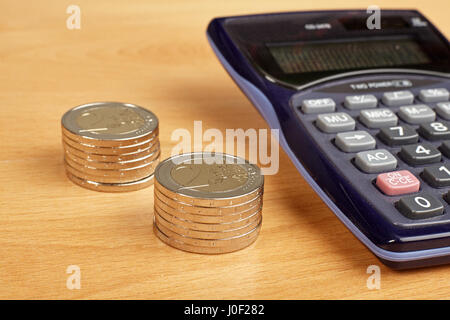 Stacks coins and calculator on wooden background. Stock Photo