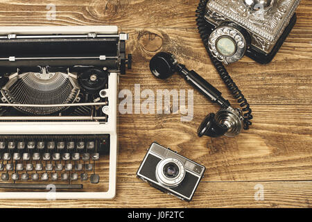 Vintage typewriter,camera and an old telephone on wooden table as business concept. Stock Photo
