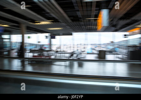 Rushing through the airport terminal to catch the next layover flight. Motion blurry image on an escalator. Last minute hurry to not to be late to the Stock Photo