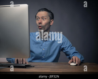 Handsome business man working on an office table with a computer Stock Photo