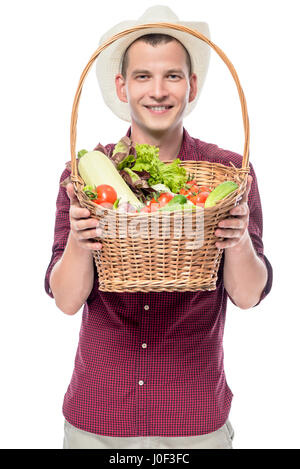 Smiling man shows a basket with grown vegetables in his garden isolated Stock Photo