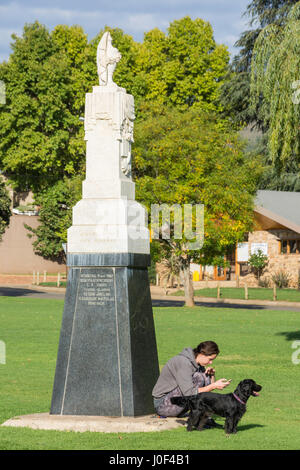 Young woman and dog by Naauwpoort Monument on The Main Square Green, Clarens, Free State Province, South Africa Stock Photo
