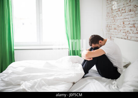 Young man having depression sitting on the bed Stock Photo