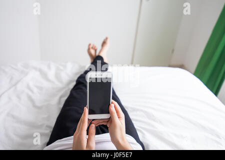 Man in his bed at home looking at mobile phone Stock Photo
