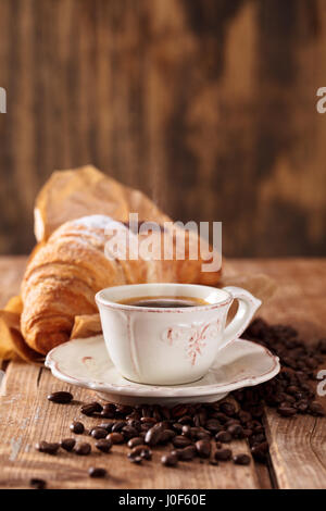 Cup of coffee on wooden table with stacked newspapers in background. Stock Photo