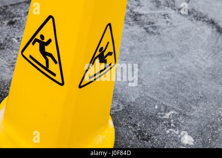Caution wet floor, yellow warning sign stands on gray asphalt urban ground, close up photo Stock Photo