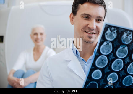 Happy positive doctor holding CT scan results Stock Photo