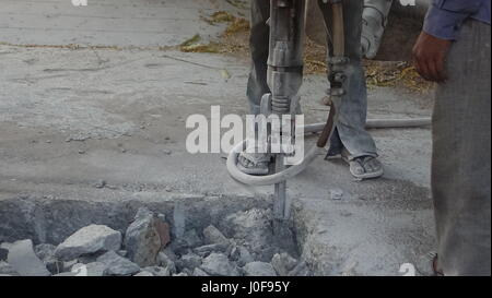 Indian blue collar workers using pneumatic hammer to drill a city pavement Stock Photo