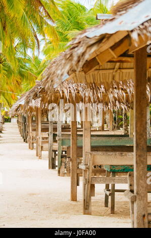 Nipa huts on the white coral sand beach surounded with palms Stock Photo