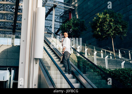 Young man caucasian outdoor in the city talking smart phone on escalator - business call, conversation, communication Stock Photo
