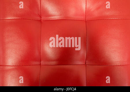 Close-up of vintage red leather couch with seams and buttons. Stock Photo