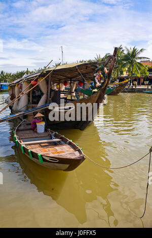 Vertical riverscape with traditional wooden long boats on the Thu Bon river in Hoi An, Vietnam. Stock Photo