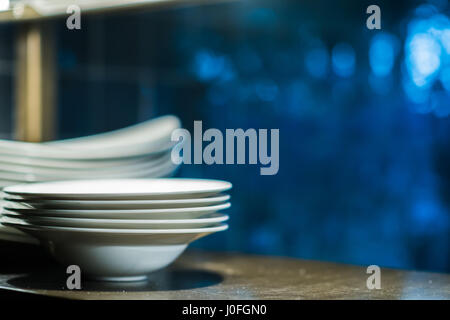 A stack of clean white porcelain plates in a restaurant kitchen Stock Photo