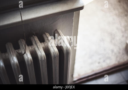 Details of an old radiator and part of a terrace in blurry background. Stock Photo