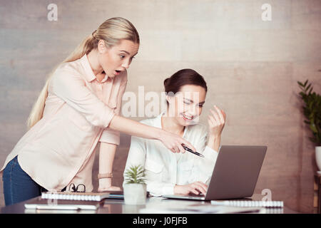 Young businesswomen using laptop and pointing with pen at screen Stock Photo