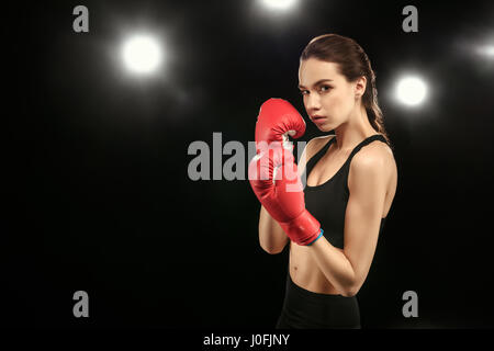 Young brunette woman in sportswear boxing on black Stock Photo