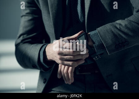 Close-up partial view of man in stylish suit using smartwatch Stock Photo