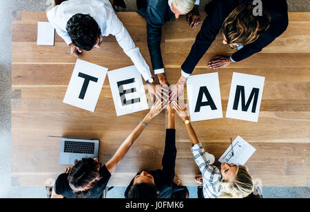 Group of business people putting their hands together over a table with work team. Top view of business team stacking hands. Stock Photo