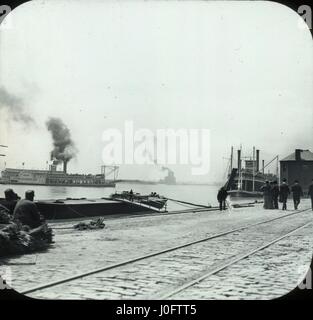 People walking along docks, steamboats in water Stock Photo