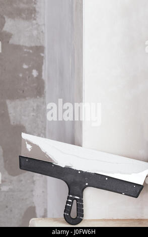 house improvement by worker puts finishing layer of stucco on the wall using a plastering trowel Stock Photo