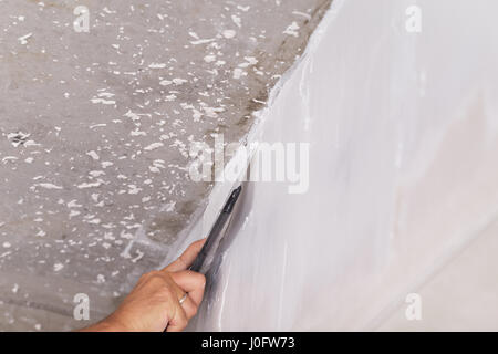 house improvement by worker puts finishing layer of stucco on the wall using a plastering trowel Stock Photo