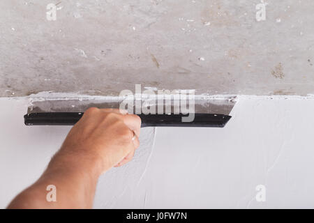 house improvement by worker puts finishing layer of stucco on the wall using a plastering trowel Stock Photo