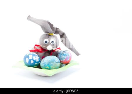 Brown cloth Easter bunny and three hand colored easter eggs - abstract colors yellow, blue, green, red, pink, purple, orange with stripes isolated in  Stock Photo