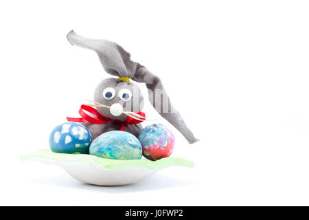 Brown cloth with red ribbon Easter bunny and three hand colored easter eggs - abstract colors yellow, blue, green, red, pink, purple, orange with stri Stock Photo
