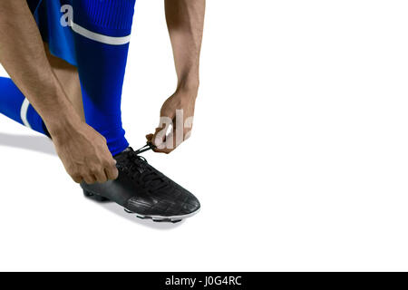 Football player tying his shoe lace against white background Stock Photo