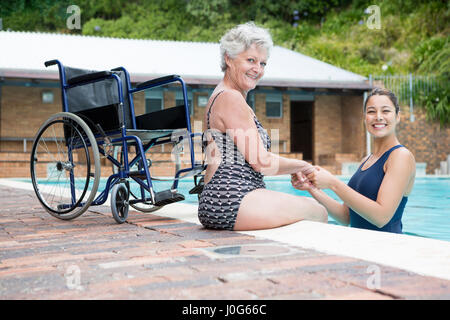 Portrait of female coach and senior woman smiling at poolside Stock Photo