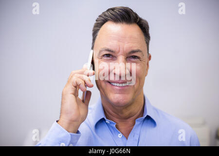 Portrait of dentist talking on mobile phone at dental clinic Stock Photo