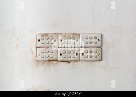 Row of Dirty Light Switches on Stained Concrete Wall Stock Photo