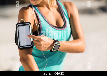 Midsection of woman using smartphone on armband at beach Stock Photo