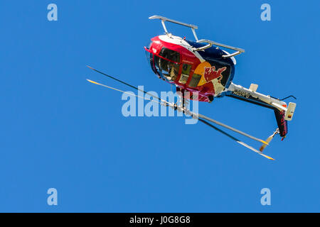 Red helicopter in the air front view, facing towards viewer on plain background performing aerobatic maneuvers, Flying bulls aerobatic display team Stock Photo