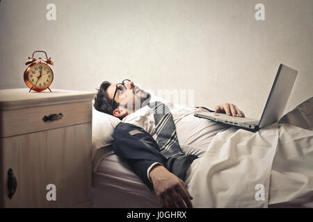 Man with laptop sleeping in bed Stock Photo