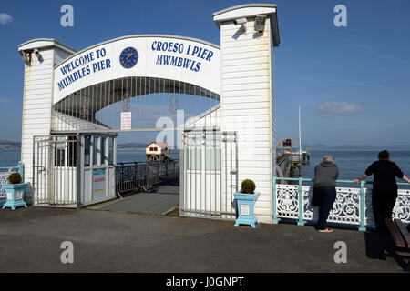 Mumbles Pier is a world famous maritime icon - the entrance with view of original lifeboat station through it, Mumbles, Swansea, UK Stock Photo